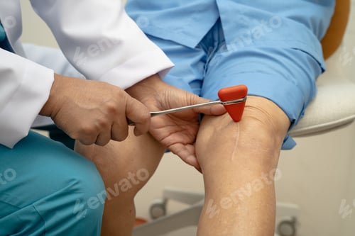Preview: Asian doctor use hammer knock senior woman patient to check knee reflex, nerve and muscle