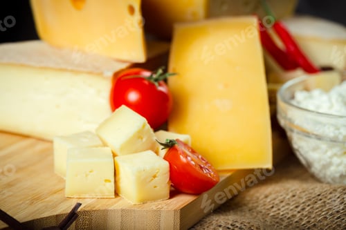 Preview: Delicious assortment of cheeses and fresh vegetables on a wooden board