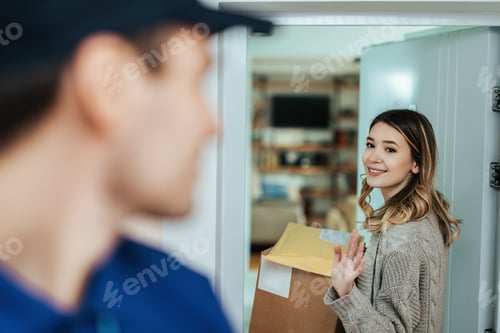 Preview: Young smiling woman waving goodbye to a delivery man.