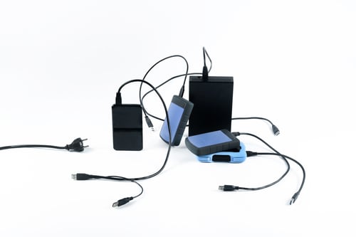 Preview: many external hard drives with wires lie on a white background. Hard drives on isolate