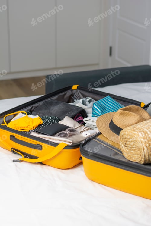 Preview: Suitcase for summer vacation on home bed or hotel room with vacation clothes on tropical ocean beach