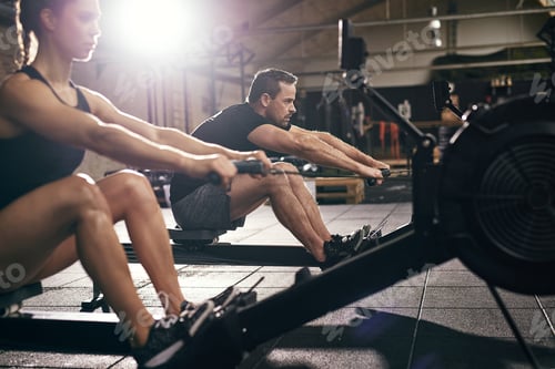 Preview: Sportsmen doing exercises with rowing machine together
