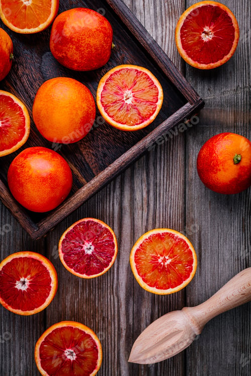 Preview: Sliced and whole ripe juicy blood oranges and grapefruit in the box on wooden background.
