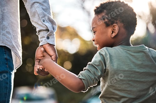 Preview: Rearview shot of a little boy holding his fathers hand while walking together outdoors