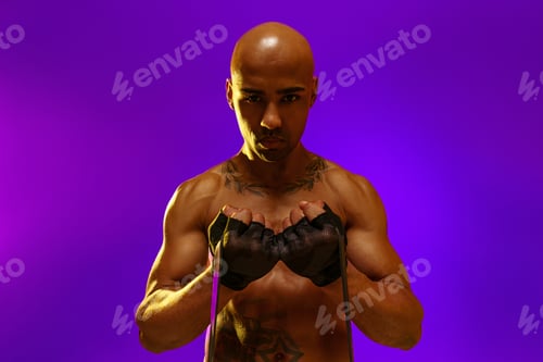 Preview: Sporty man performs exercises with expander on studio background. Strength and motivation