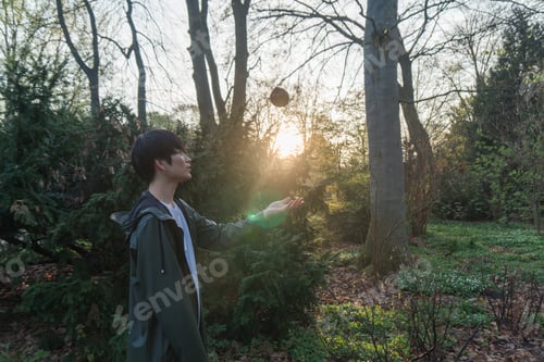 Preview: Man throwing a ball vertically and standing in woods