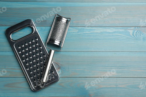 Preview: Modern graters on light blue wooden table, flat lay. Space for text
