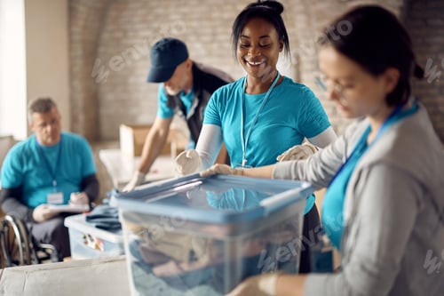 Preview: Happy volunteers packing donated clothes into boxes at community center.