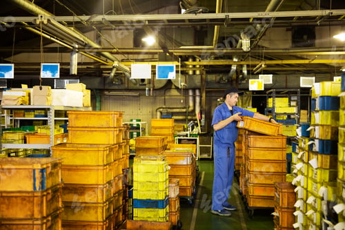Preview: Japanese man stacking orange plastic crates.