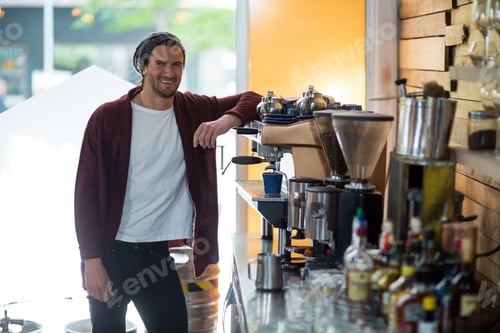Preview: Portrait of smiling owner standing near espresso machine