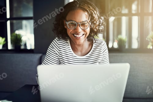 Preview: Smiling young African woman using a laptop