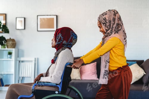 Preview: Caring muslim child helping parent in wheelchair with disability to live happy life