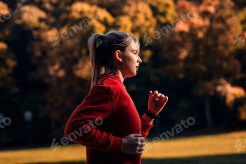 Preview: Side view of young woman running in park.