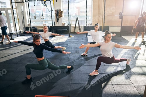 Preview: Concentrated fit women performing a yoga pose together at gym