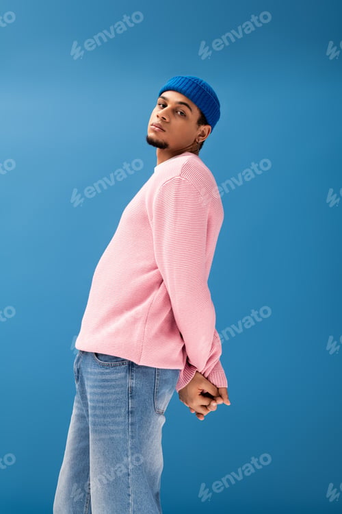 Preview: Fashionable young man showcases style against bright blue backdrop in modern attire