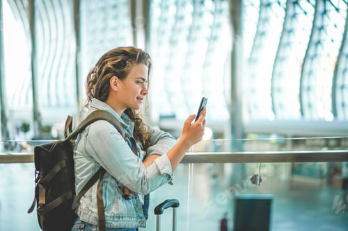 Preview: A beautiful young woman using a mobile phone at the airport