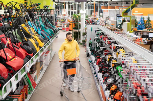 Preview: lawn mower shop customer walks between rows of battery electric petrol lawn mowers