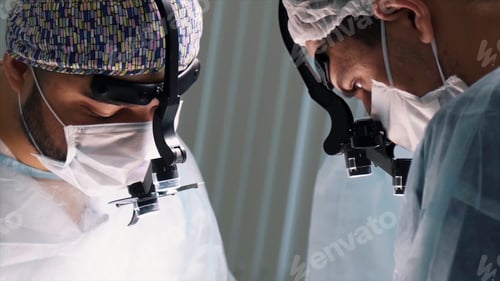 Preview: Medical team performing operation. Action. Close up of faces of surgeons at work wearing binocular