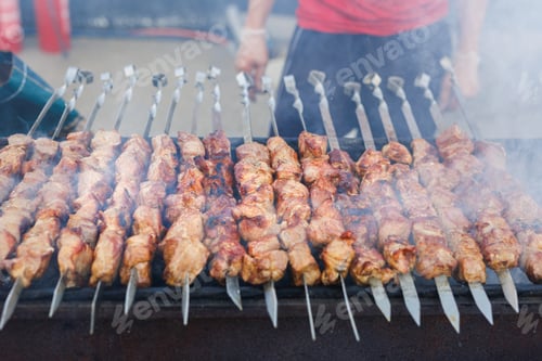 Preview: Succulent and delicious grilled meat skewers on the bbq rack with flames and sparks.
