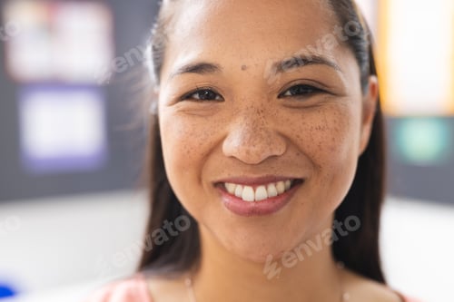 Preview: A young biracial female teacher with freckles is smiling in a classroom