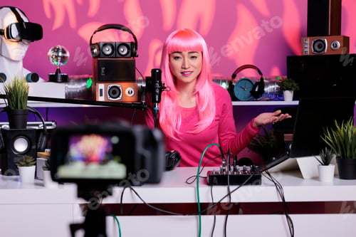 Preview: Happy vlogger with pink hair recording podcast while talking with remote subscribers in vlogging