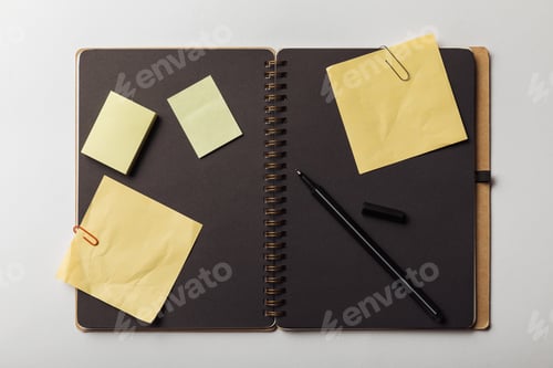 Preview: top view of opened notebook with black sheets and yellow sticky notes with paper clips on white