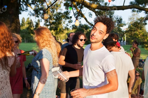 Visualização: Retrato de homem adulto médio em festa lotada ao pôr do sol no parque