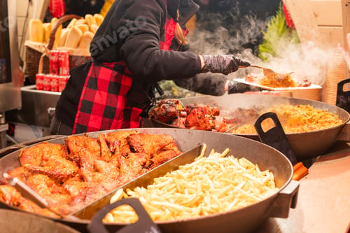 Preview: vendor fries meat and sausage on the grill in the city center at the Christmas market