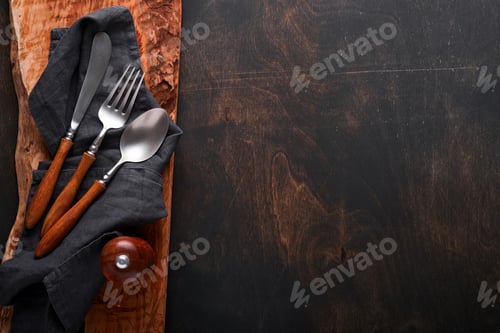 Preview: Vintage silverware. Rustic vintage set of wooden spoon and fork on wooden platter on black wooden ba