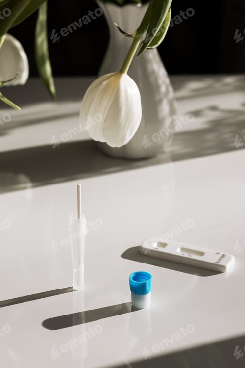 Preview: tablet and covid and disease test kit next to the tulip on a white background