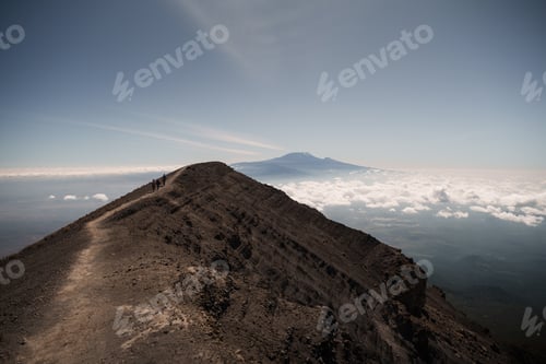Preview: Hikers walking on the crater rim of mount meru, with mount kilimanjaro in the background