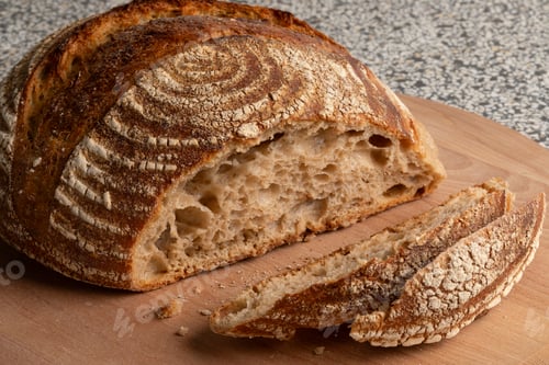 Preview: aditional homemade sourdough bread and slices on a cutting board close up