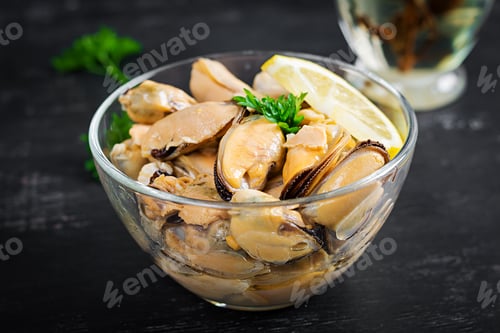 Preview: Delicious mussel meat with lemon and fresh parsley on a dark background.