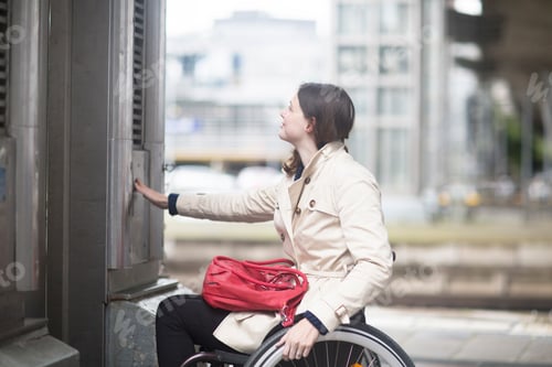Preview: Young woman using wheelchair pressing control for city elevator