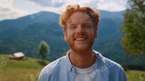 Preview: Portrait happy man smiling on green meadow. Red hair guy relaxing on vacation.