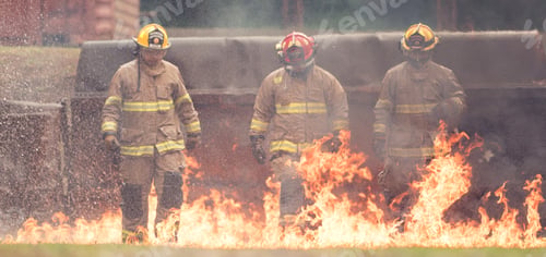 Preview: A group of firefighters in full protective gear walks through ground flames
