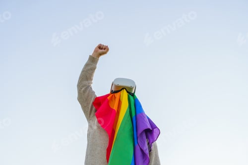 Preview: Man raising his fist in the air in protest while wearing an LGBT flag