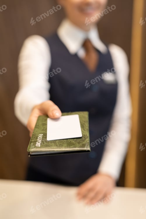 Preview: Hand of young receptionist in uniform standing in front of camera and passing passport to guest