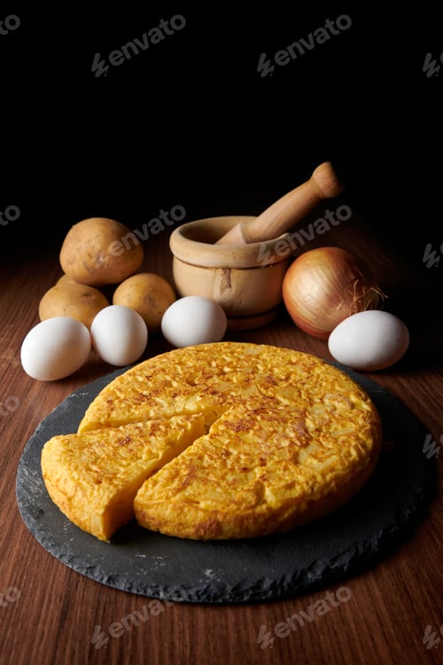 Preview: Closeup of a fresh tasty Spanish omelette and the ingredients on the background
