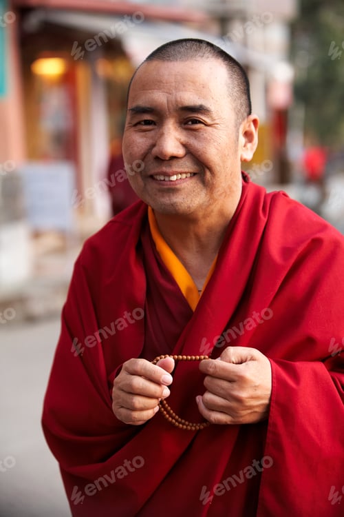 Preview: Smiling monk in traditional robes holding prayer beads