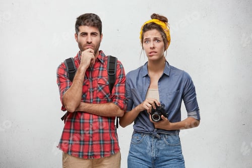 Preview: Portrait of worried young stylish woman holding camera, biting her lips, frustrated with problems wh