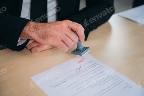 Preview: Businessman hand stamping an approved stamp on a text document at a table with a contract form paper