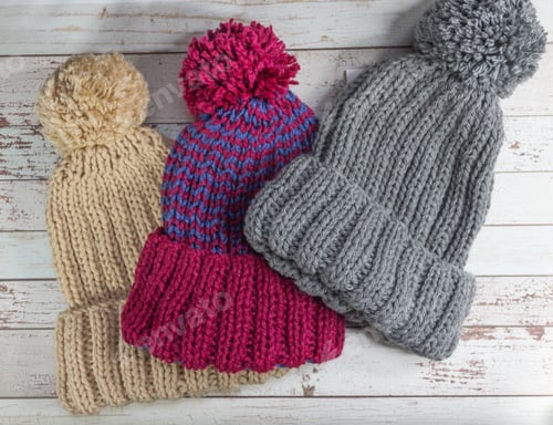 Preview: hand knitted wool hats on rustic wooden background and autumn leaves