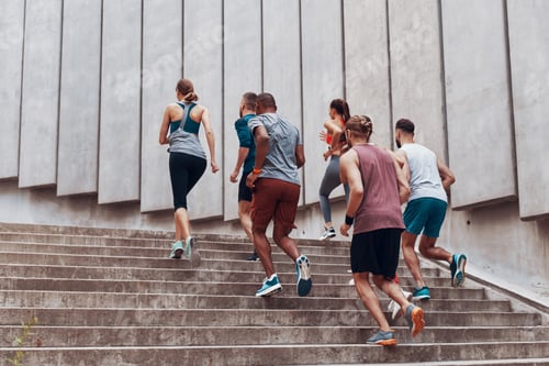 Preview: Full length of young people in sports clothing jogging while exercising on the stairs outdoors