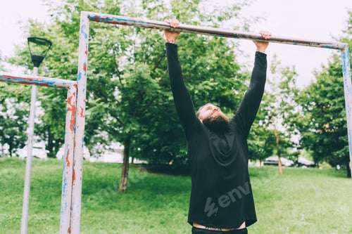 Preview: Young handsome caucasian bearded sportsman doing pull-up outdoor