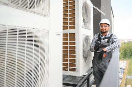 Preview: Indian Repairman in uniform installing the outside unit of air conditioner