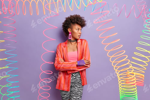 Preview: Beautiful model with serious expression, has stylish curly hair, stands in confident pose, looks awa