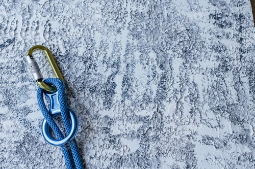 Preview: Isolated photo of climbing equipment. Part of carabiner lying on the white and grey colored surface