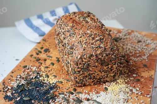 Preview: Freshly baked organic sourdough loaf of multi-seeded bread on wooden board.