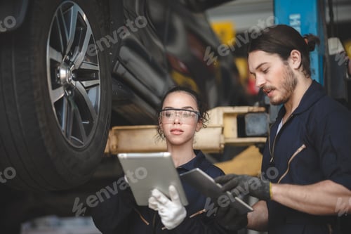 Preview: car mechanic standing under car in garage inspecting and doing maintenance work for car
